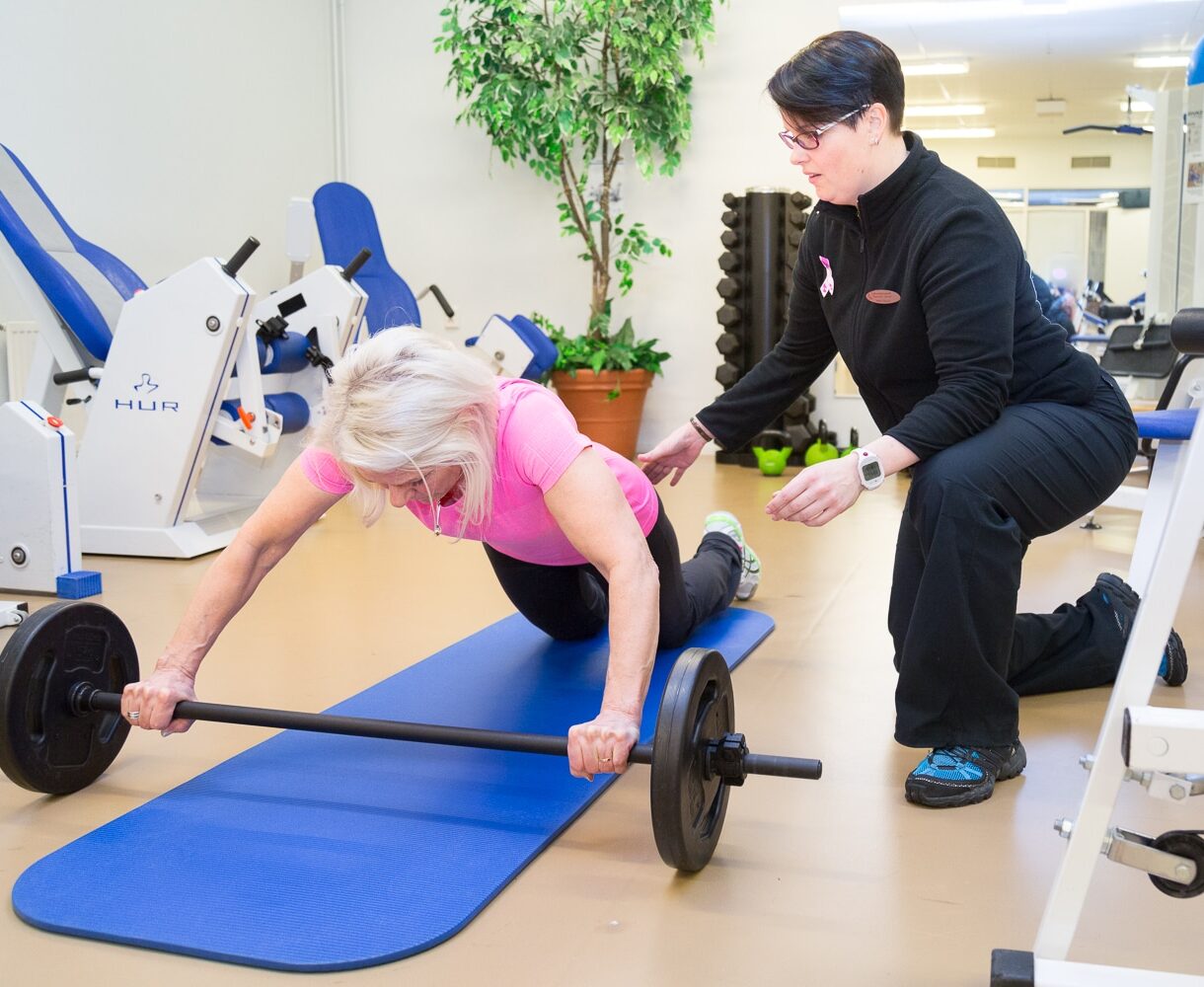 Personal trainer ohjaa asiakasta kuntosalilla.