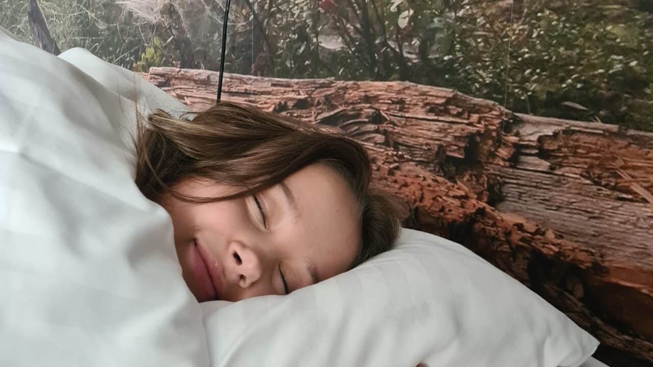 Tyttö nukkuu makeasti valkoisten hotellilakanoiden välissä Kunnonlähde Kankaanpään hotellissa.