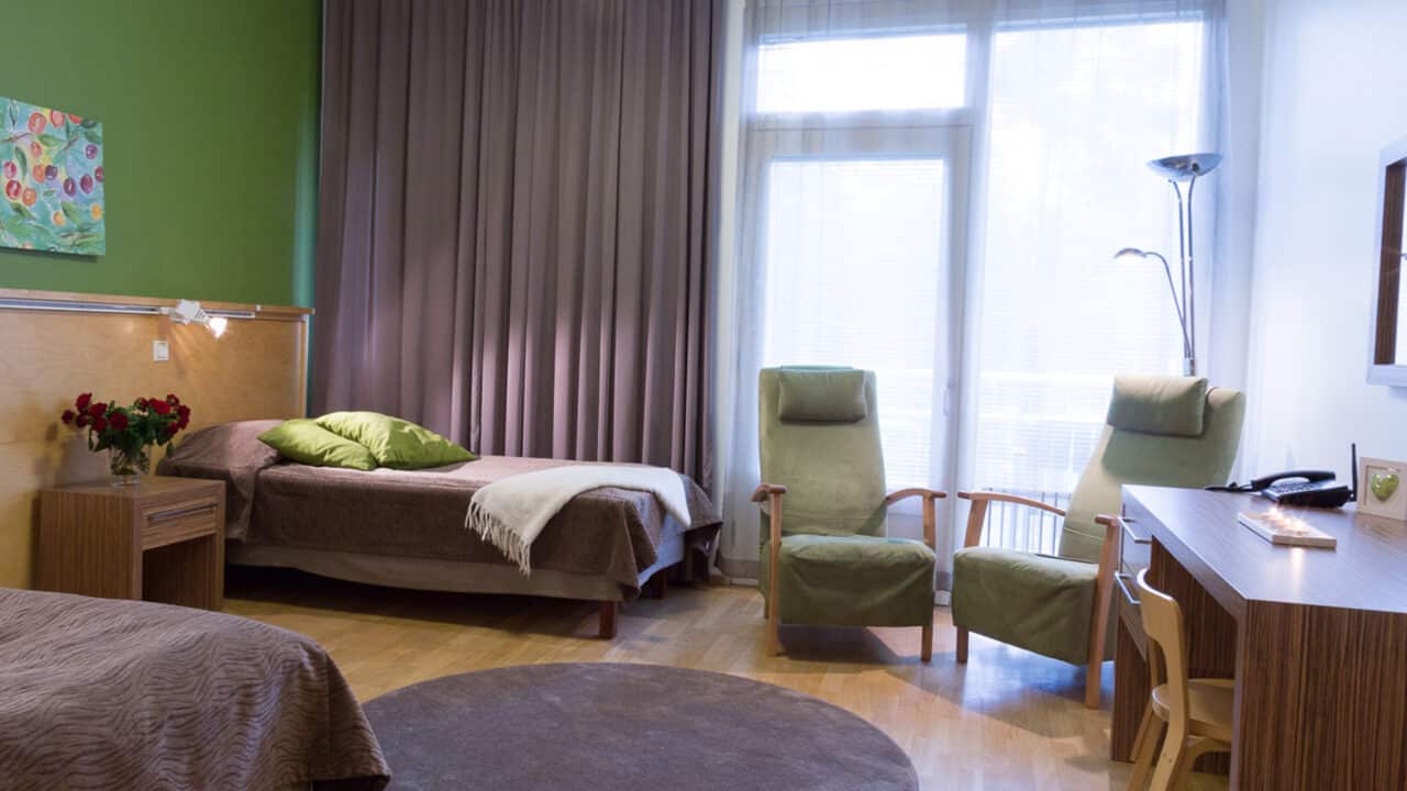 Hotellihuone, jossa rauhalliset vihreän ja ruskean sävyt.