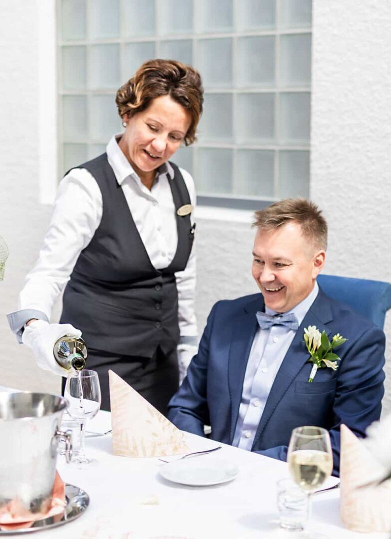 Tarjoilija kaataa viiniä asiakkaalle ravintolassa