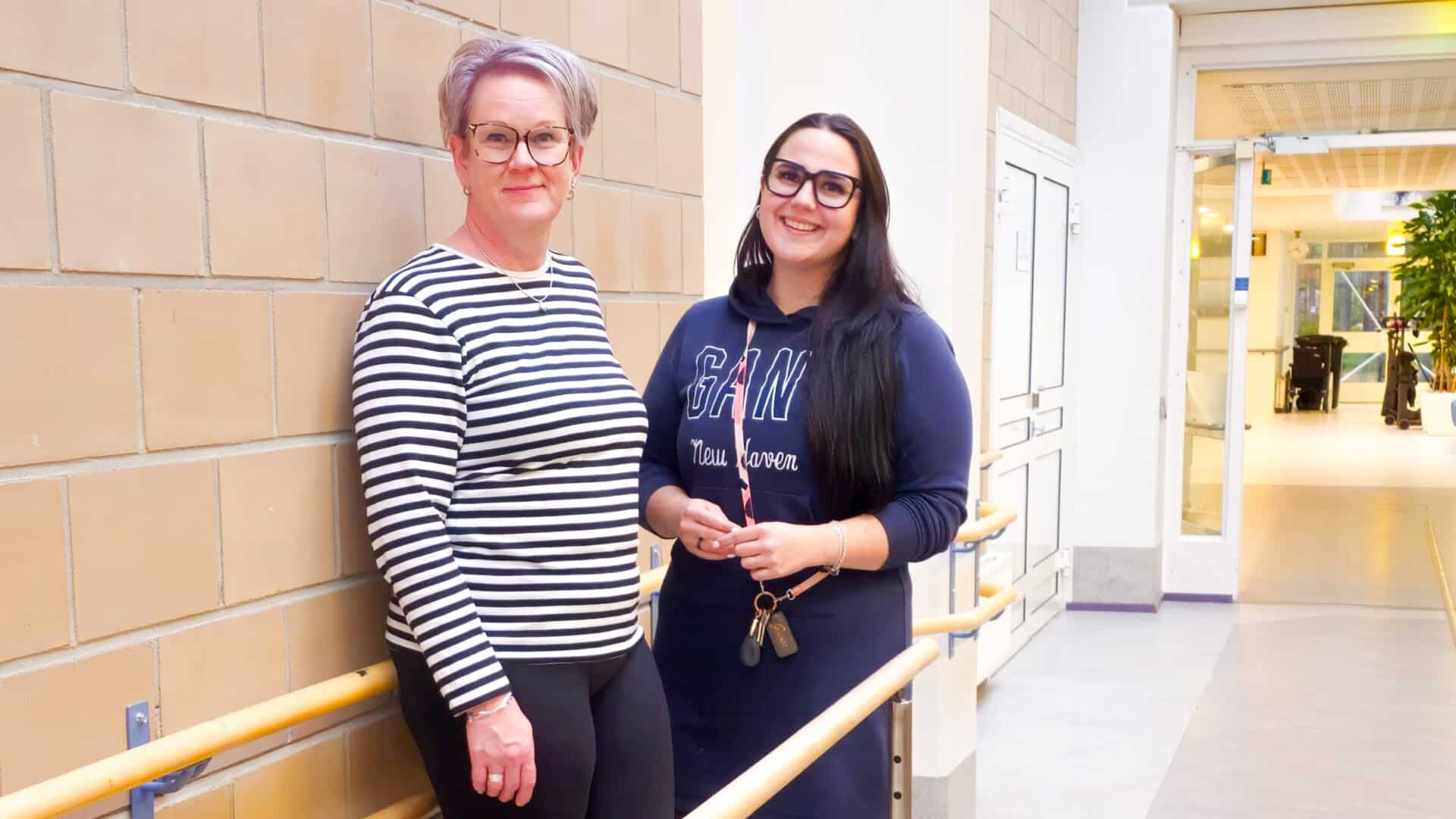 Kelan moniammatillisen yksilökuntoutuksen asiakas Kirsi Mäkilä ja Kunnonlähteen sairaanhoitaja Pipsa Laholuoma seisovat hymyilevinä käytävällä.